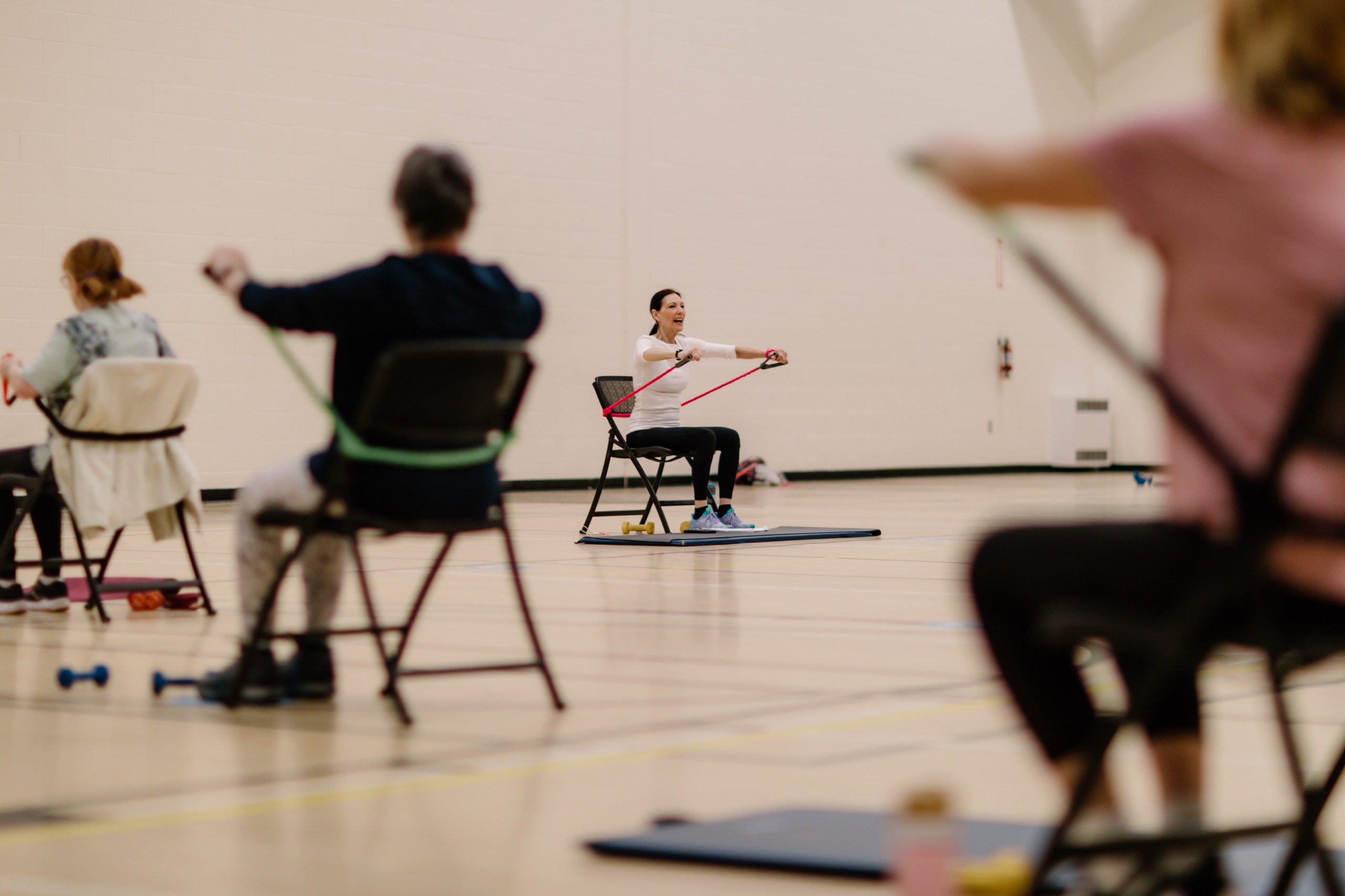 Seniors group fitness class, with participants using resistance bands for an upper body exercise
